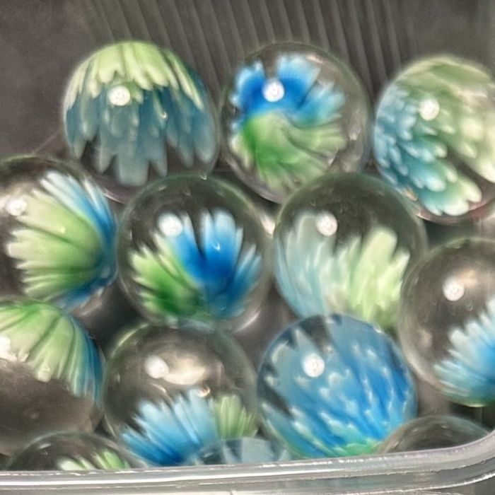 Bloesem groen-blauw 25mm: handgemaakte knikker in helder glas met een bloem in groen en blauw