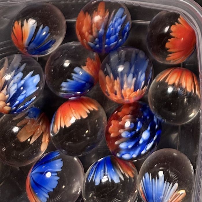 Bloesem oranje-blauw 25mm: handgemaakte knikker in helder glas met een bloem in oranje en blauw