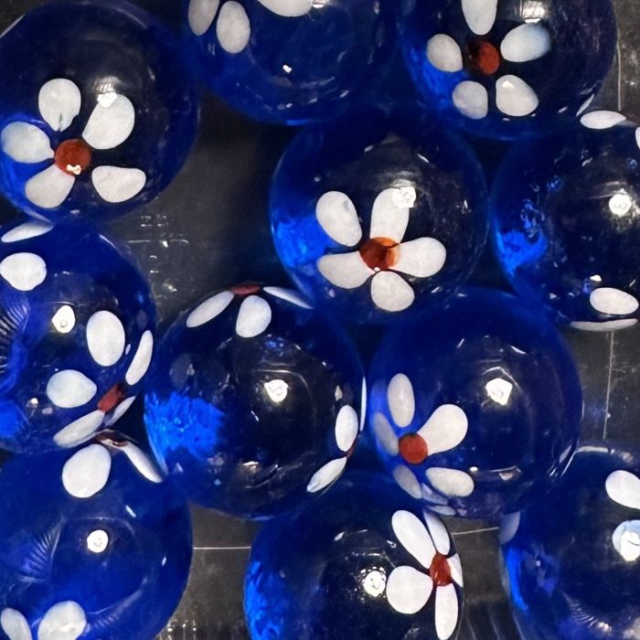 Lente donkerblauw 16mm: handgemaakte knikker in doorschijnend donkerblauw glas met witte bloemetjes met een rood hartje