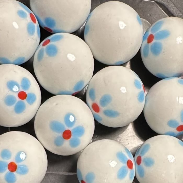 Lente wit-lichtblauw 25mm: handgemaakte knikker in wit glas met lichtblauwe bloemetjes met een rood hartje