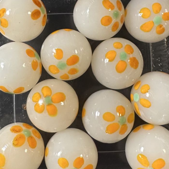 Lente wit-oranje 16mm: handgemaakte knikker in melkwit glas met oranje bloemetjes met een lichtgroen hartje